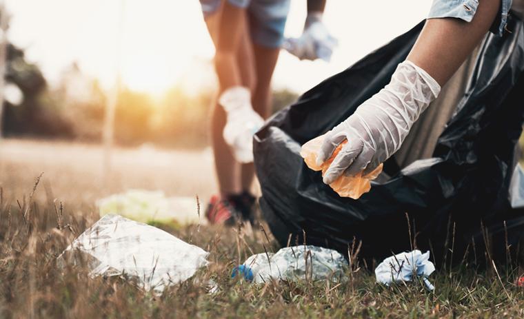 A woman’s hand picking up garbage at a park