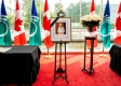 Photo de la Reine avec un ruban noir sur le cadre à côté d’un bouquet de fleurs entouré de drapeaux